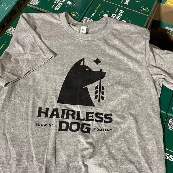 Photograph of a light gray tee shirt with black Hairless Dog Brewing Company logo, lying across a case of Hairless Dog Black Ale cartons